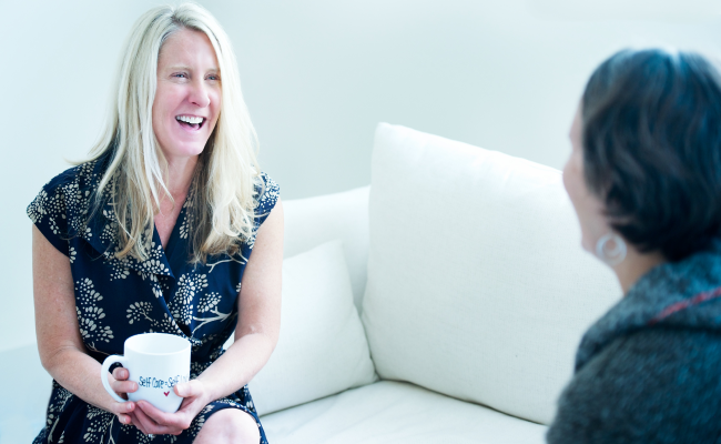 Tanya Mark holding a coffee cup while having a one-to-one coaching session with a client.